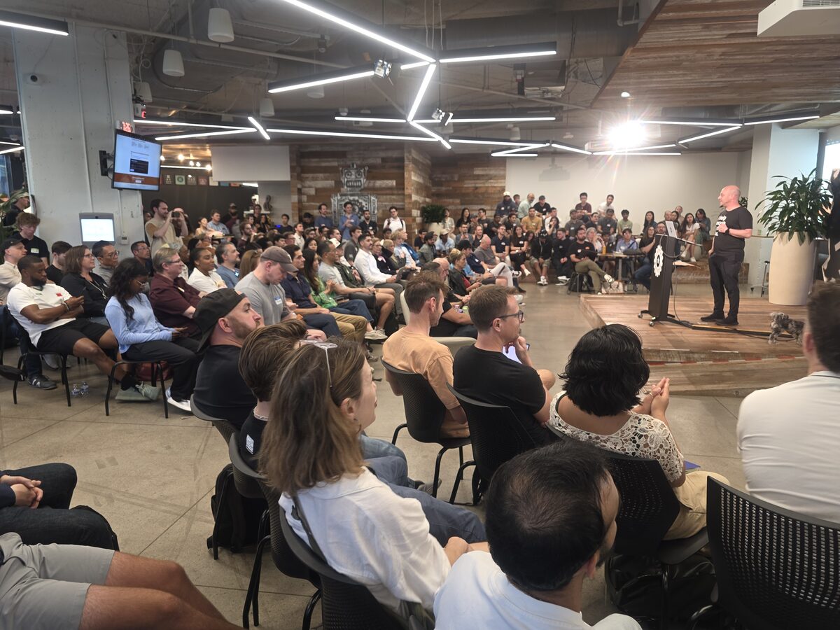 A packed audience watches a speaker at the Claude Code meetup